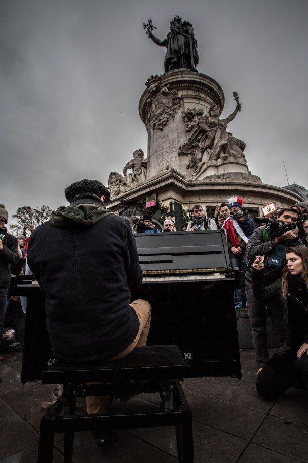 Un musicien joue quelques notes, place de la République, pour habiller le silence.
